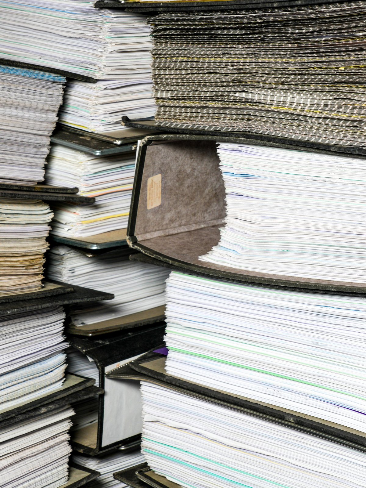 Carpetas de documentos contables densamente apiladas con facturas, mostrando archivo de oficina y carga administrativa